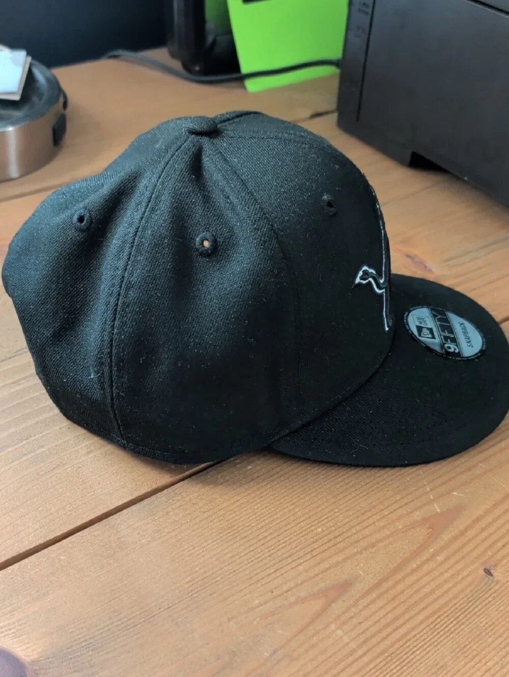 New Era Black Snapback Hat with Gray-Outlined Lion Patch